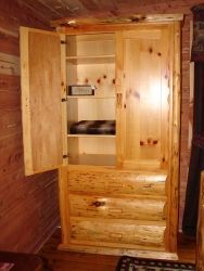 A wooden wardrobe with the doors open in a room.