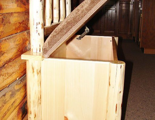 A wooden box with the lid open is next to a wooden railing