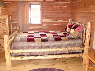 A log cabin bedroom with a bed and a window.