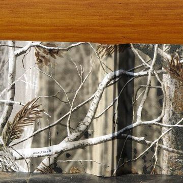 A wallet with a camo pattern on it sits on a wooden table