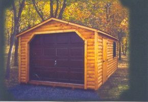 A wooden garage with a black door is surrounded by trees