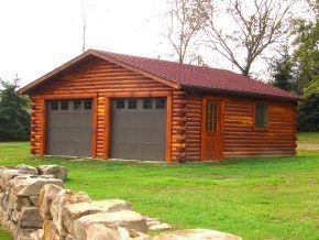 A log cabin with two garage doors is sitting in the middle of a lush green field.