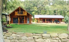 A large log cabin is sitting in the middle of a lush green field.