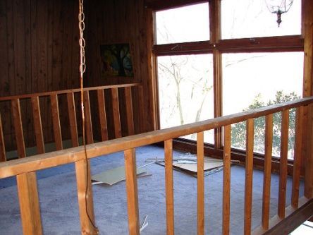 An empty room with a wooden railing and lots of windows