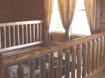 A wooden railing leading to a window in a cabin