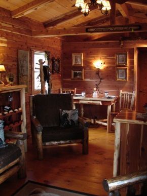 A living room in a log cabin with a chair and a table