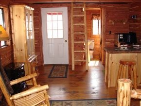A living room in a log cabin with a rocking chair and a ladder