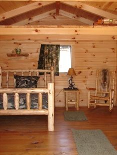A bedroom in a log cabin with a bed and chairs