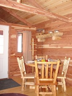 A dining room in a log cabin with a table and chairs