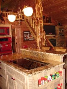A kitchen in a log cabin with a stove top oven and a microwave.