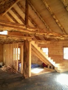 A wooden house with stairs going up to the second floor.