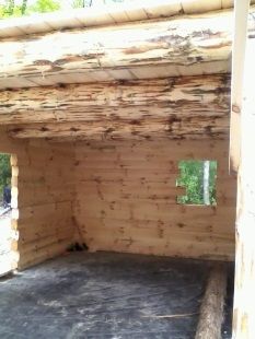 A wooden room with a window and a roof made of logs.