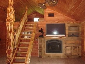 A living room in a log cabin with stairs and a fireplace