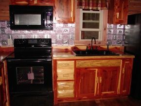 A kitchen with wooden cabinets , a stove , microwave , sink and refrigerator.
