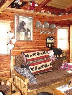 A living room in a log cabin with a couch and chairs