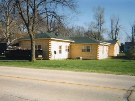 A small house with a green roof is on the side of the road