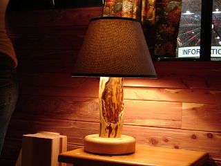 A lamp is sitting on a wooden table next to a window.