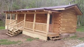 A small log cabin with a porch and stairs.