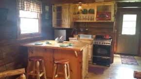 A kitchen in a log cabin with a table and stools.