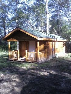 A small wooden cabin with a porch in the woods