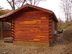 A small log cabin with a porch in the woods