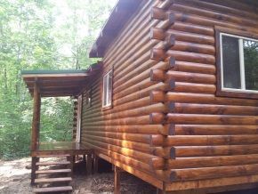 A log cabin with stairs and a porch in the woods