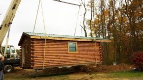 A crane is lifting a log cabin into the air.