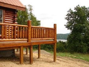A log cabin with a wooden deck overlooking a lake