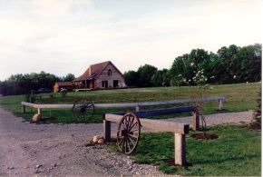 A wooden fence with a wagon wheel in front of a house