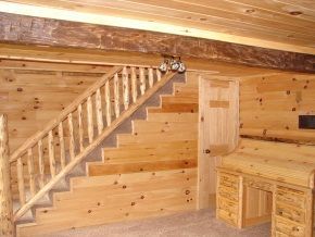 A wooden staircase in a cabin with a desk underneath it