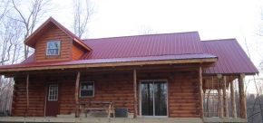 A log cabin with a red roof and a porch.