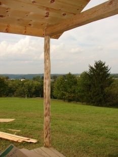 A wooden pergola is sitting in the middle of a grassy field.