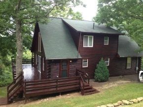 A large log cabin with a green roof and a large deck