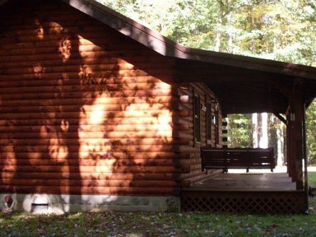 A log cabin with a porch in the woods