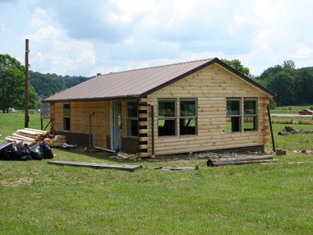 A small house is being built in a grassy field