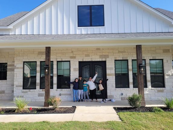 A group of people are standing in front of a house.