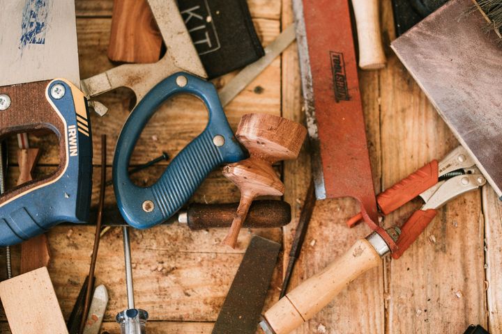 Hand saws and woodworking tools on a workbench with wood shavings and scraps