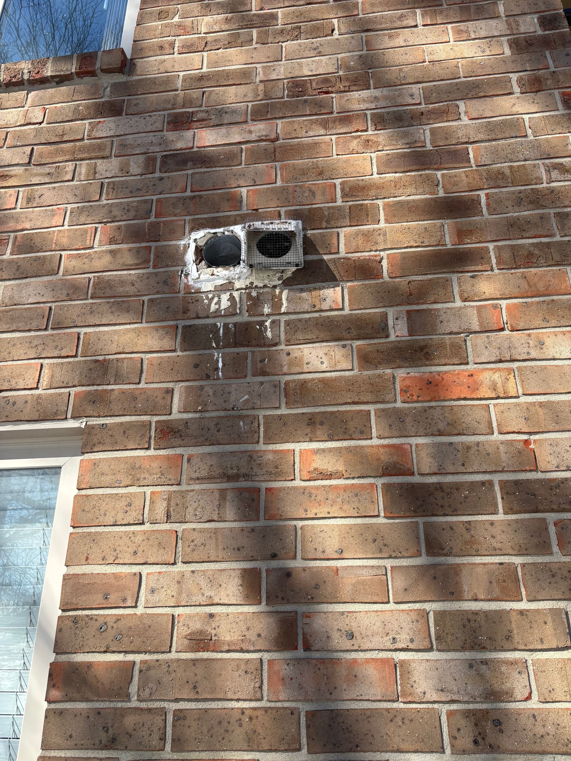A brick wall with a hole in it and a window.