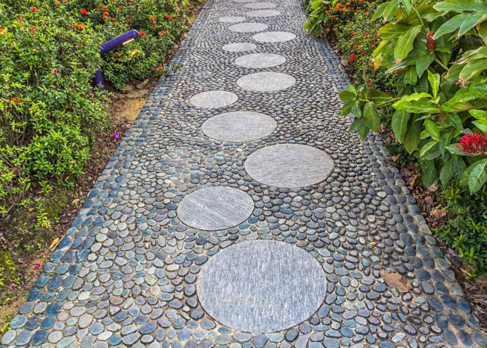 Affordable Stone Walkway with Small Stones and Large Circular Pavers Bordered by Garden