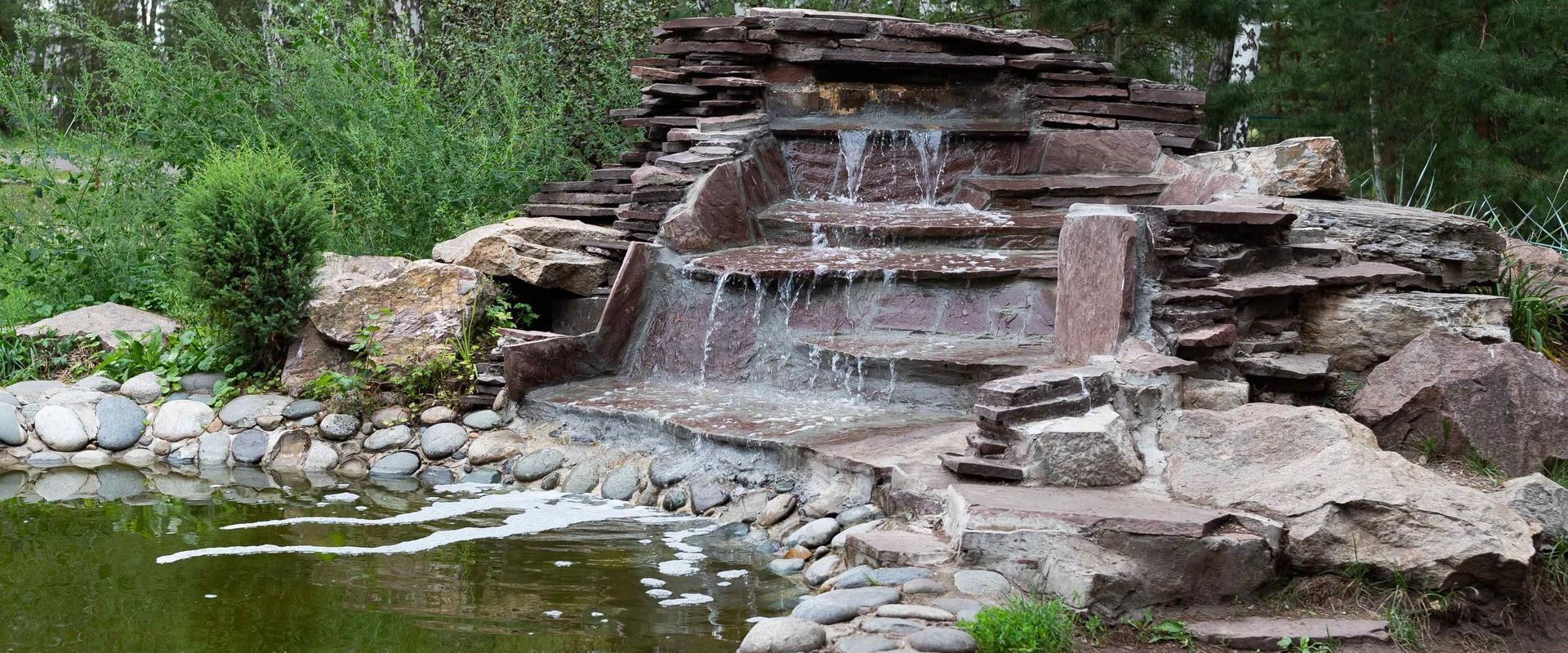 Landscaped Backyard Waterfall Flowing Into Pond