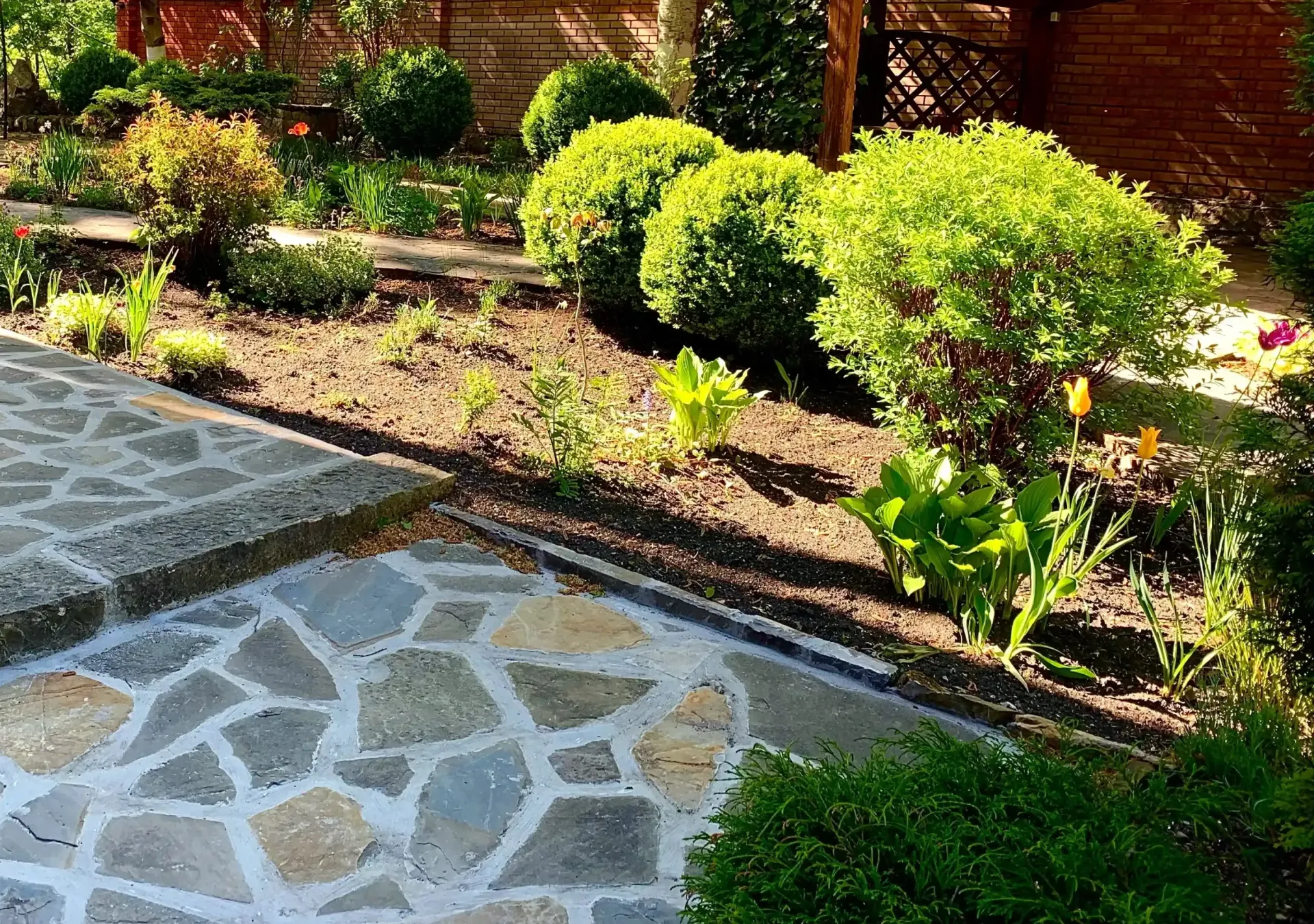 Landscaped Backyard With Stone Patio Shrubs And Covered Sitting Area