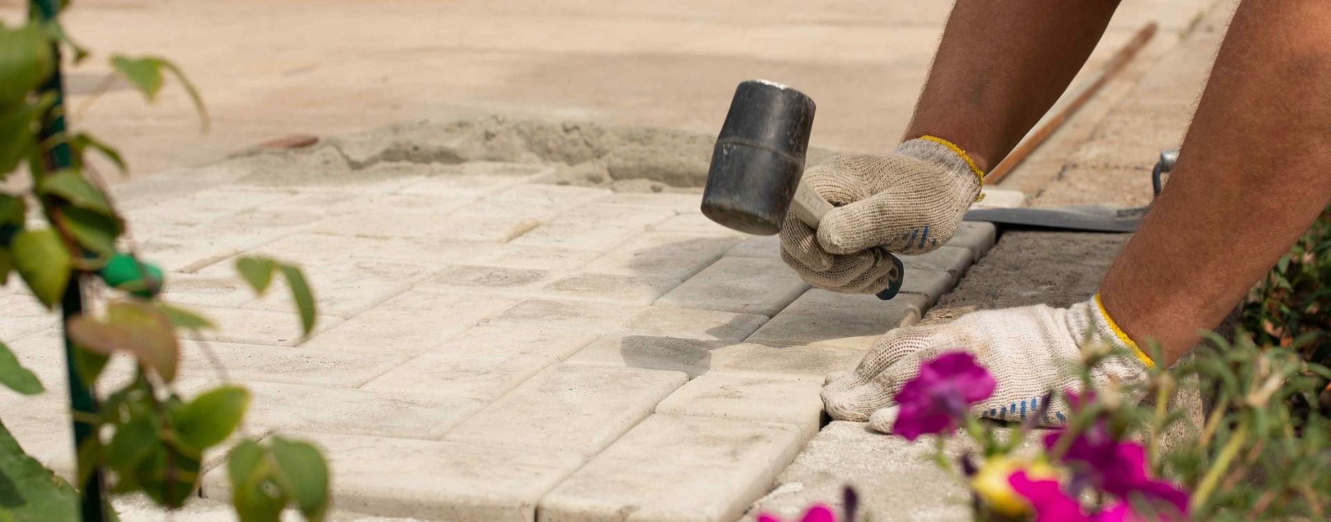 Worker Using Rubber Mallet To Install Pavers