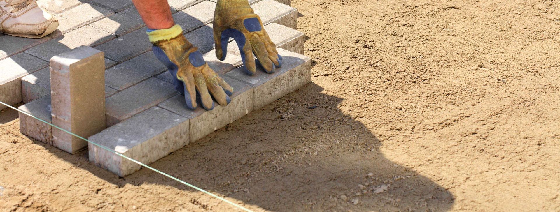 Worker Placing Pavers On Sand Base