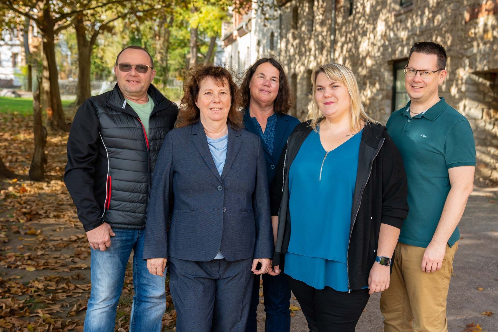 Das Team der BT Bestattungstreuhand GmbH steht nebeneinander vor einem Gebäude.