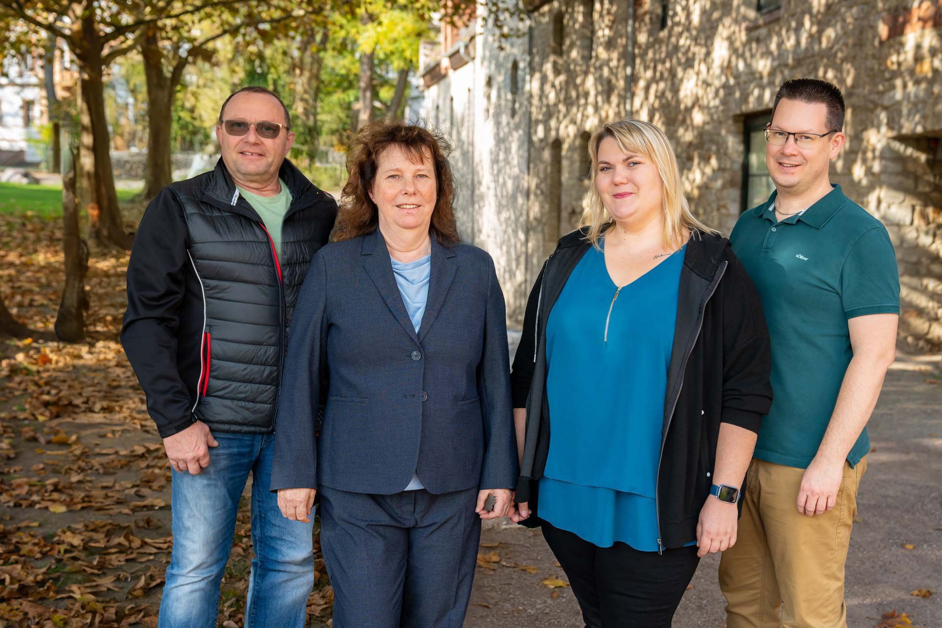 Das Team der BT Bestattungstreuhand GmbH steht nebeneinander vor einem Gebäude.