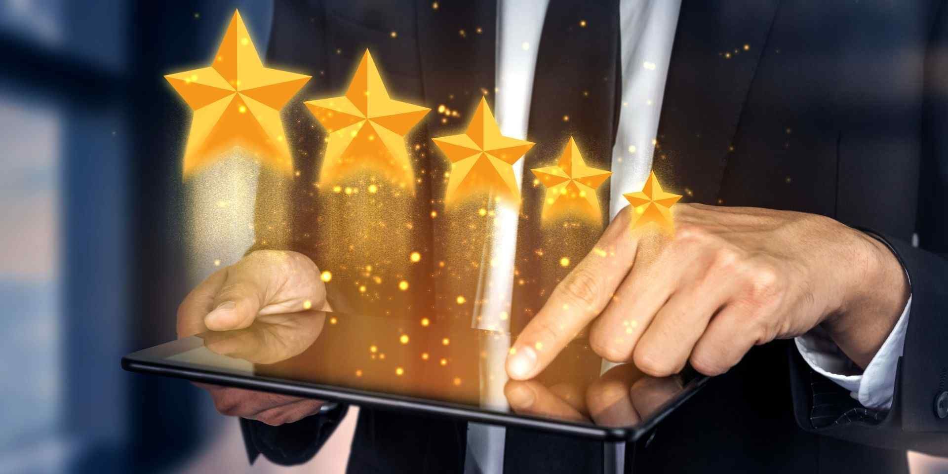 A man in a suit is holding a tablet with stars coming out of it for high reviews