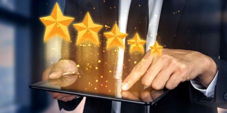 A man in a suit is holding a tablet with stars coming out of it.