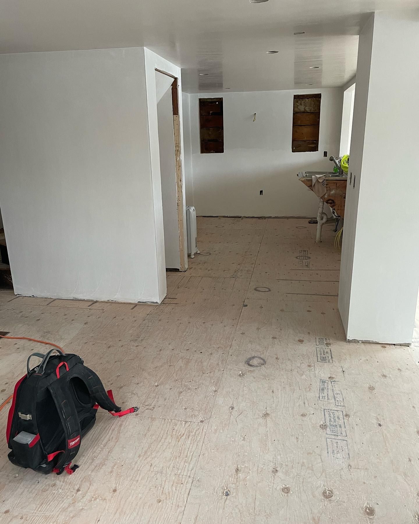 A backpack is sitting on the floor of a room under construction.