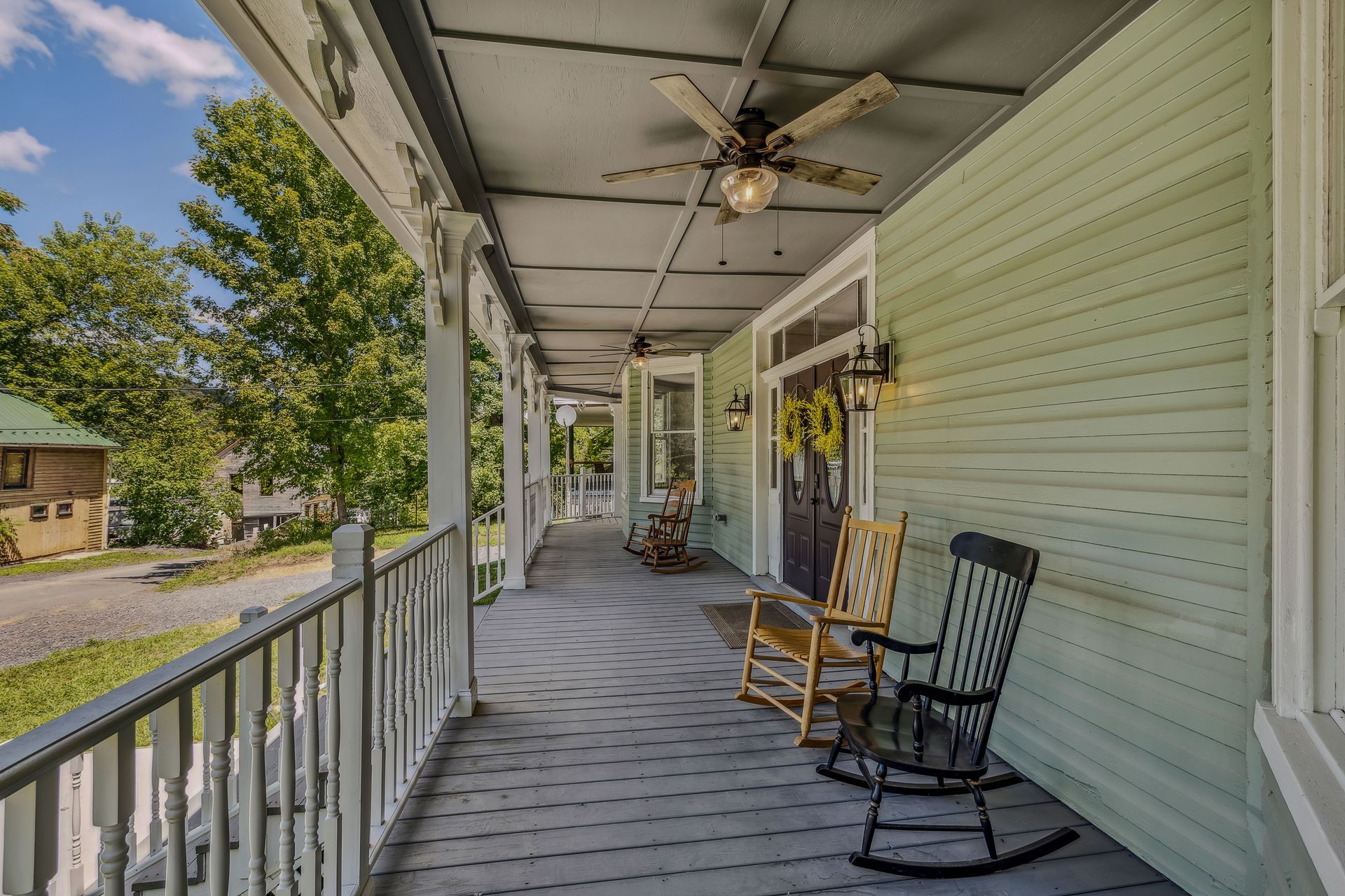 There are two rocking chairs on the porch of a house.