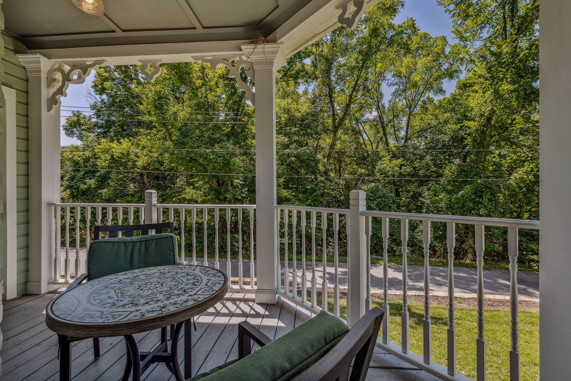 A porch with a table and chairs and trees in the background.